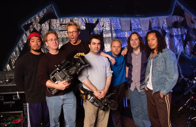 Men standing together with video cameras and microphones.
